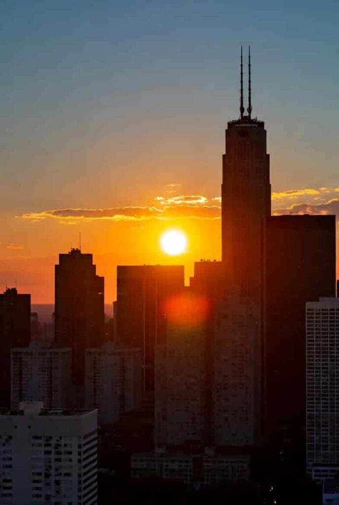 City skyline at dusk early evening, sun setting earlier, daylight savings 2025 impact on evening light”