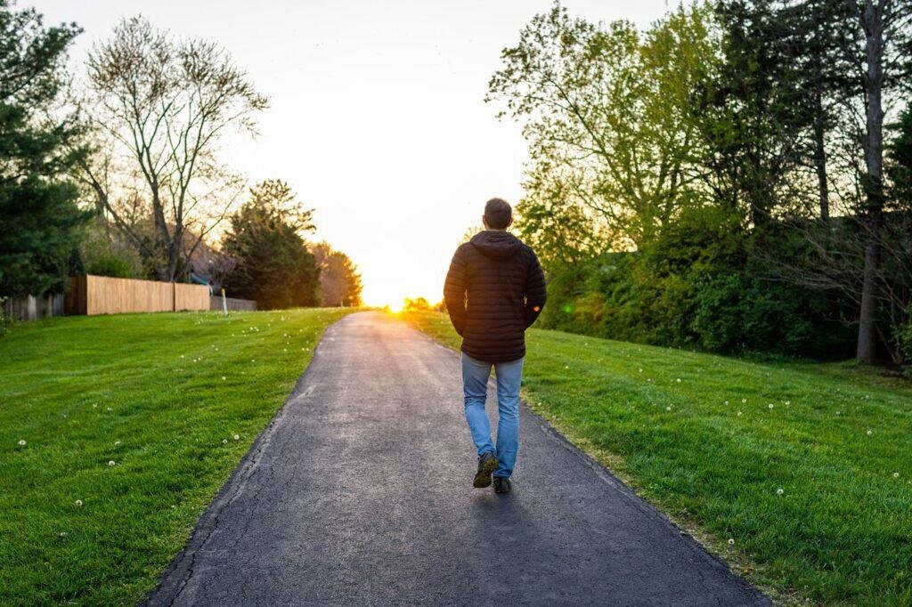 A person walking in a park during morning sunlight, looking relaxed and fresh.