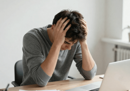 Person experiencing brain fog from poor gut health sitting at desk with head in hands looking mentally exhausted